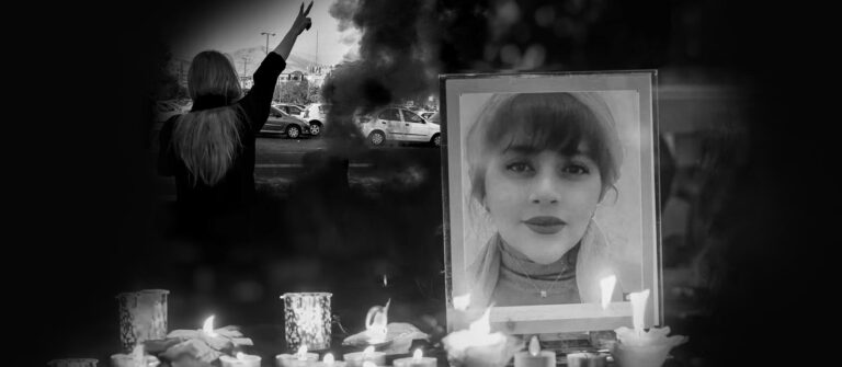 Framed picture of Mahsa Amini on the right, line of candles in the foreground, figure of woman with a raised arm in the background. Black and white.