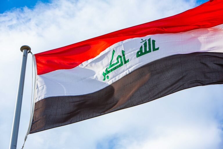 Flag of Iraq against cloudy sky.